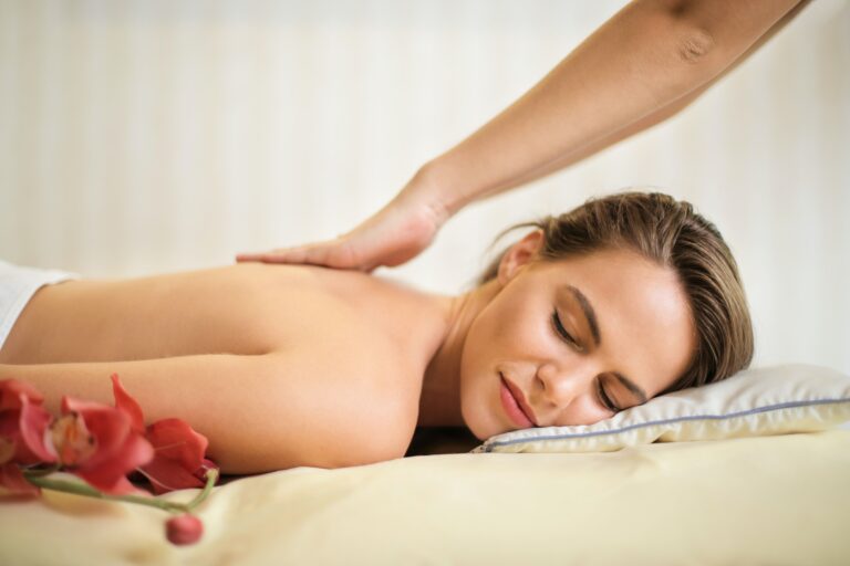 Frau auf einer Massage-Liege, die von Masseur am Rücken berührt wird.